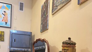 Huoneessa on puinen lipasto, peili, patsas ja jalustalla oleva televisio.