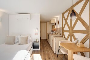 Ein modernes Hotelzimmer mit Bett, Nachttisch und einer kleinen Küchenzeile.