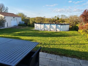 Ein Garten mit Pool, Terrasse und Gartenhaus.