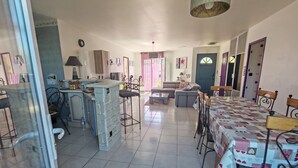 Uma sala de estar ampla com mesa de jantar, sofá e cozinha.