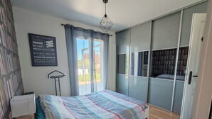 Quarto com cama, estante, guarda-roupa e janela com cortinas.