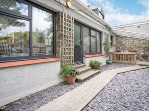 A building with large windows, a stone facade, and a wooden deck. - Brewery Cottage (Saundersfoot)