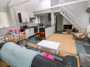 A modern apartment with a kitchen, dining area, living room, and a staircase. - Brewery Cottage (Saundersfoot)