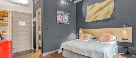 Ein Schlafzimmer mit einem Bett, einem großen abstrakten Gemälde, einer modernen Decke und einem roten Gerät.