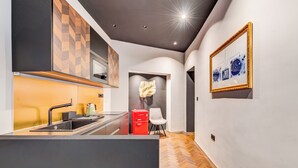 Una cucina moderna con un'isola centrale, un elettrodomestico rosso e un quadro appeso al muro.