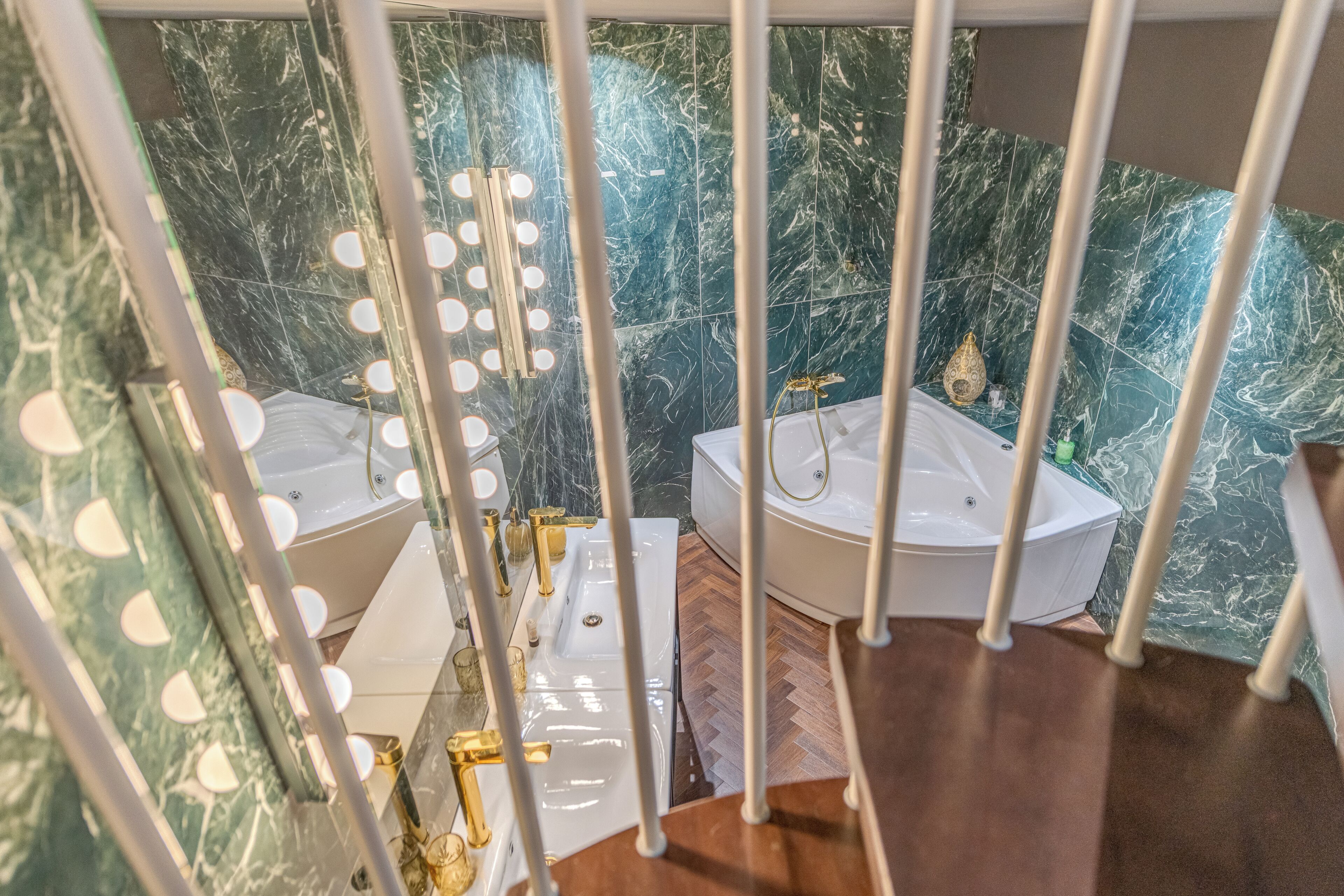 A bathroom with two sinks, a bathtub, and a mirror with lights.