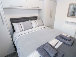 Una cama bien hecha con ropa de cama a rayas, un cabecero gris y una toalla gris al lado.
