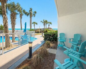 Ein Poolbereich mit Liegestühlen, Palmen und Blick aufs Meer.