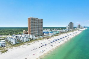A coastal hotel area with beachfront properties, a long sandy beach, and a clear blue sky. - Palm Beach B12 - Beachfront 1BR, Ground Level, Pool/Gulf View, Heated Pool, Gym (Orange Beach)