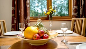 A dining table with a fruit bowl, wine glasses, and a bottle.
