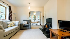 A living room with a sofa, a TV, a fireplace, and a window with curtains.