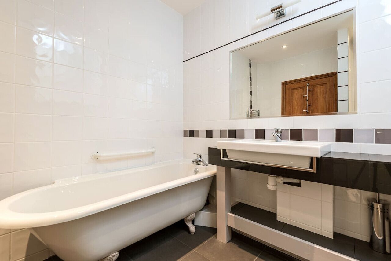 Un baño moderno con una bañera independiente, un tocador con espejo y un mueble de madera.