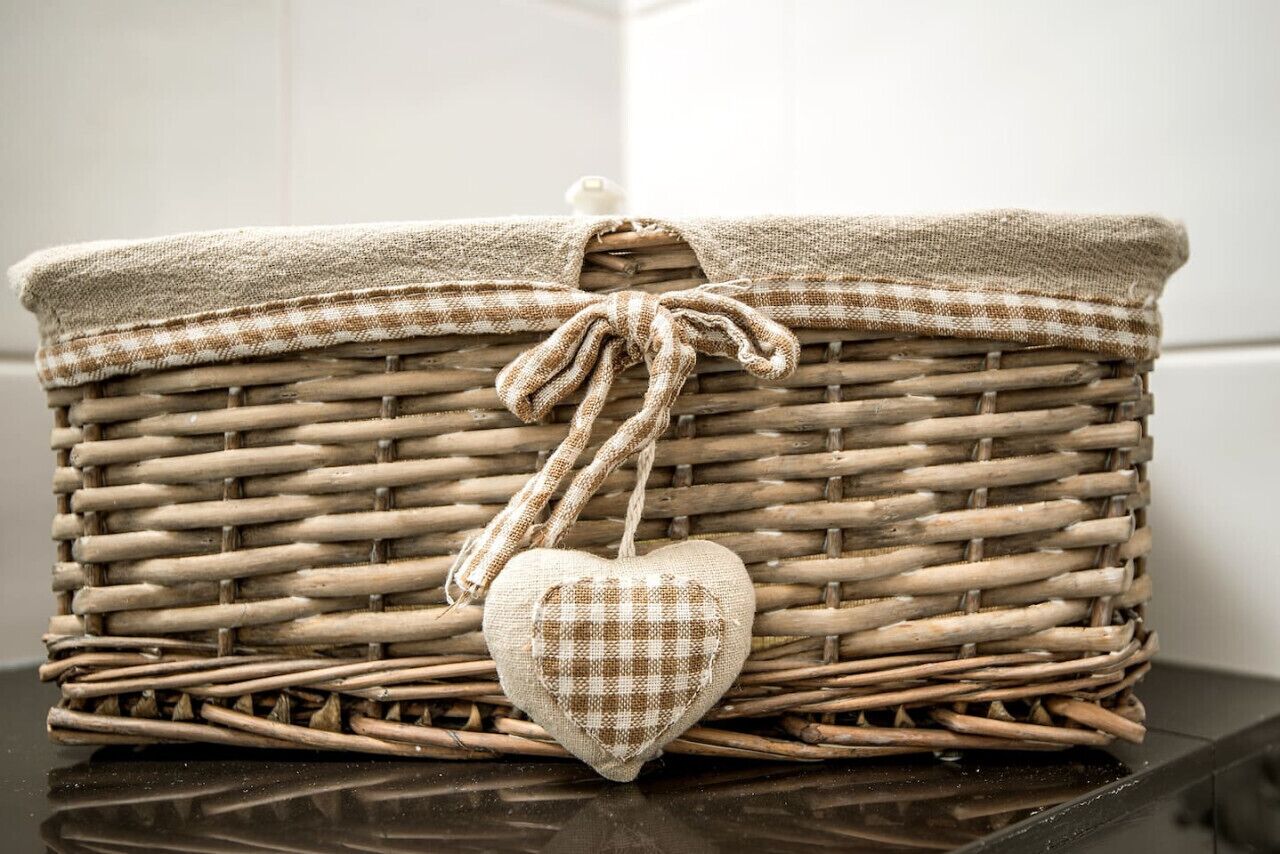 A wicker basket with a checkered fabric cover and a heart-shaped decoration.
