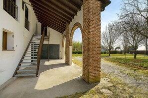 A building with a staircase, brick columns, and a covered area with a bench. - Apartment 'Alessia' with Shared Pool, Garden, and Wi-Fi (Jesolo)