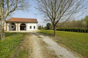 Ein Gebäude mit rotem Ziegeldach, Rundbogenöffnungen und einem Kiesweg, der davor führt.