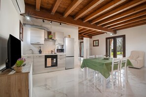 Une cuisine moderne avec des meubles blancs, un réfrigérateur et un coin repas agrémenté d’une nappe verte.
