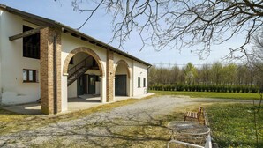 A building with a brick facade, arched entrance, and a gravel driveway. - Apartment 'Marina' with Shared Pool, Garden, and Wi-Fi (Jesolo)