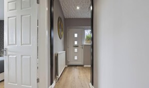 Ein Flur mit einer weißen Tür, einem Heizkörper und einer Decke mit geometrischem Muster.