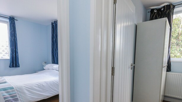 A bedroom with a bed, a wardrobe, and a radiator. - Clifftop House (Bournemouth)