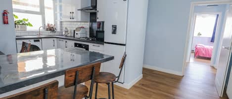 A modern kitchen with a central island, bar stools, a stove, and a refrigerator.