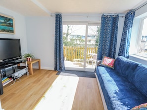 A living room with a television, sofa, and a view of the outdoors. - Clifftop House (Bournemouth)
