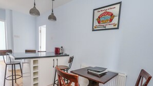 A kitchen with a dining area, a refrigerator, a toaster, and a framed sign on the wall. - Clifftop House (Bournemouth)