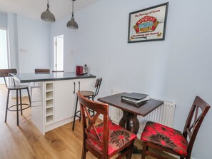 A kitchen with a dining area, a refrigerator, a toaster, and a framed sign on the wall. - Clifftop House (Bournemouth)