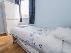 A bedroom with a bed, a wardrobe, and a window with curtains.