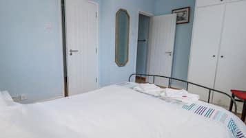 A bedroom with a bed, a wardrobe, a mirror, and a door.