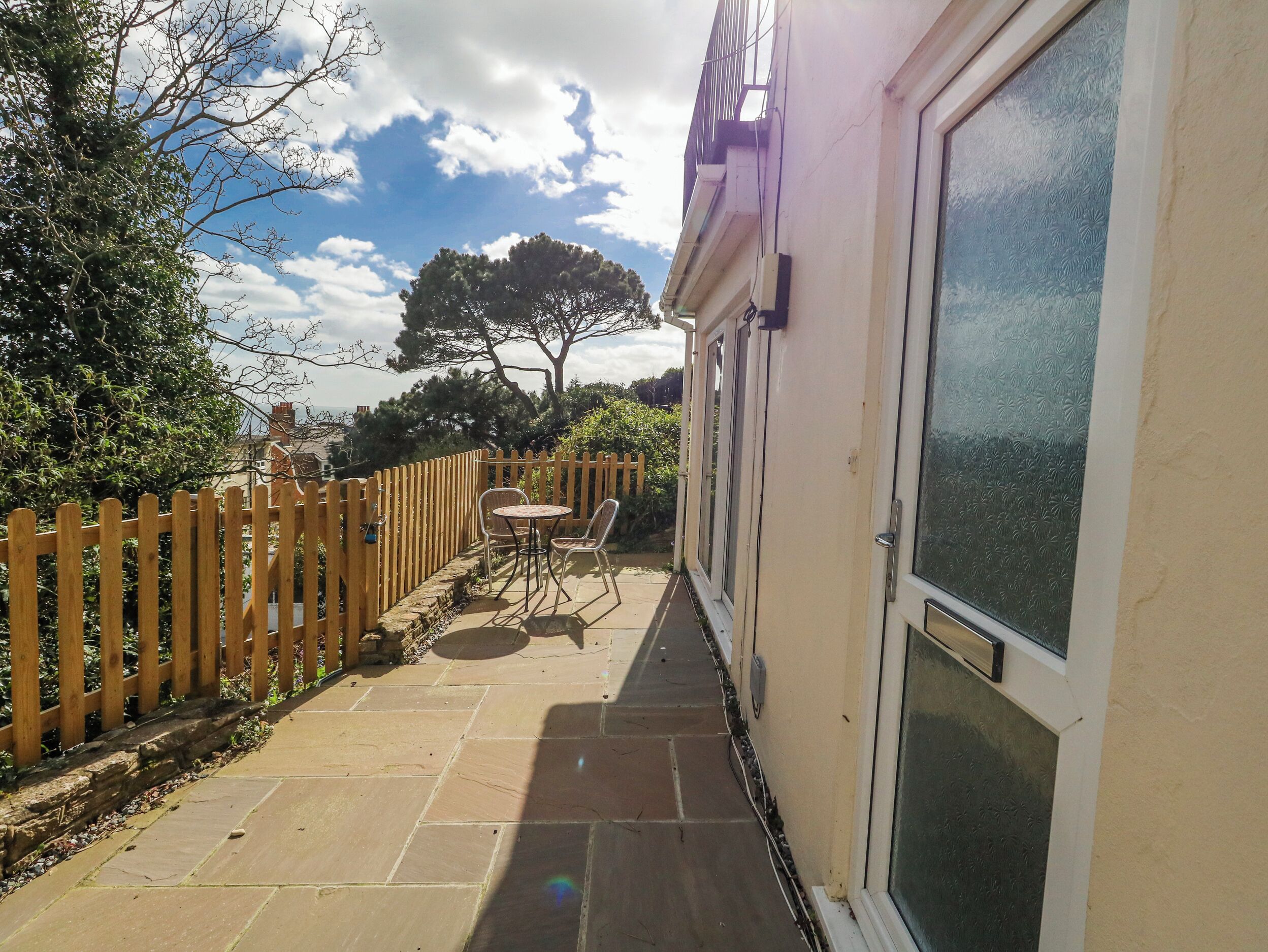 A patio with a table and chairs, a wooden fence, and a building with a glass door.