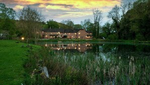 A large house with a pond in front, surrounded by trees and grass. - Clinkum Cottage Swimming Lake, BBQ hut, Games Room (Alton Towers & Staffordshire Villages)