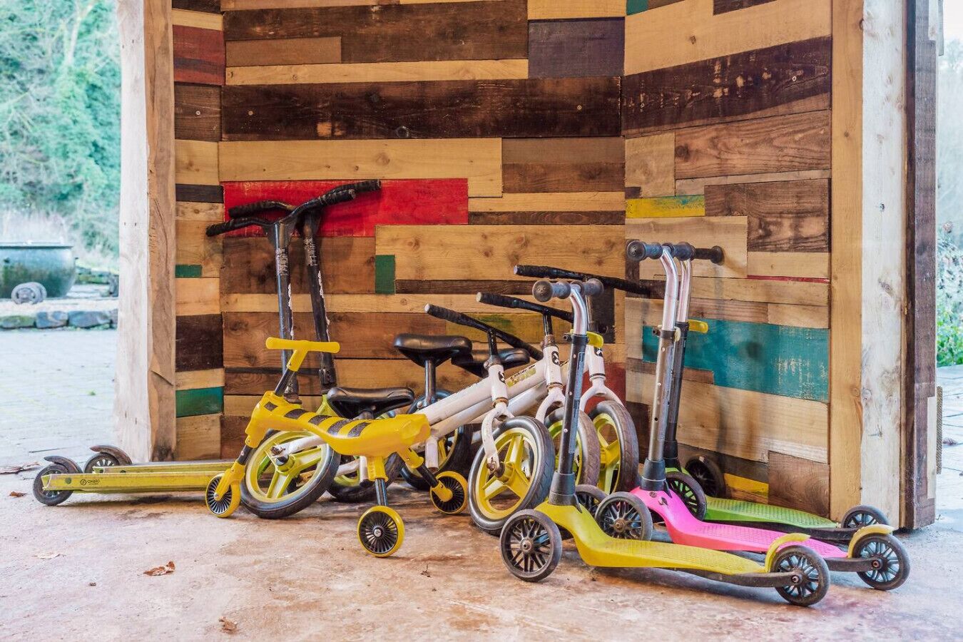 Une rangée de vélos d’appartement et de scooters est garée contre un mur en bois.