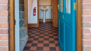 A narrow hallway with a checkered floor, a blue door, a white sink, and a fire extinguisher. - Wysteria: Swimming Lake, BBQ hut, Games Room (Alton Towers & Staffordshire Villages)