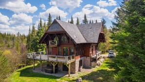 Une cabane en rondins avec une terrasse, entourée de forêt.