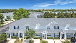 A multi-story residential building with a uniform exterior, multiple entry points, and a parking lot. - Windsor Hills 3BR Disney Townhome w/ Private Pool (Kissimmee)