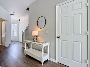 A hallway with a white console table, a lamp, and a door. - Windsor Hills Cozy Family Retreat w/ Private Pool (Kissimmee)
