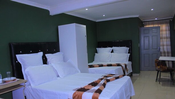 A hotel room with two beds, a wardrobe, a desk with a chair, and a dining table. - ablrine home&lode  (Cape Town)
