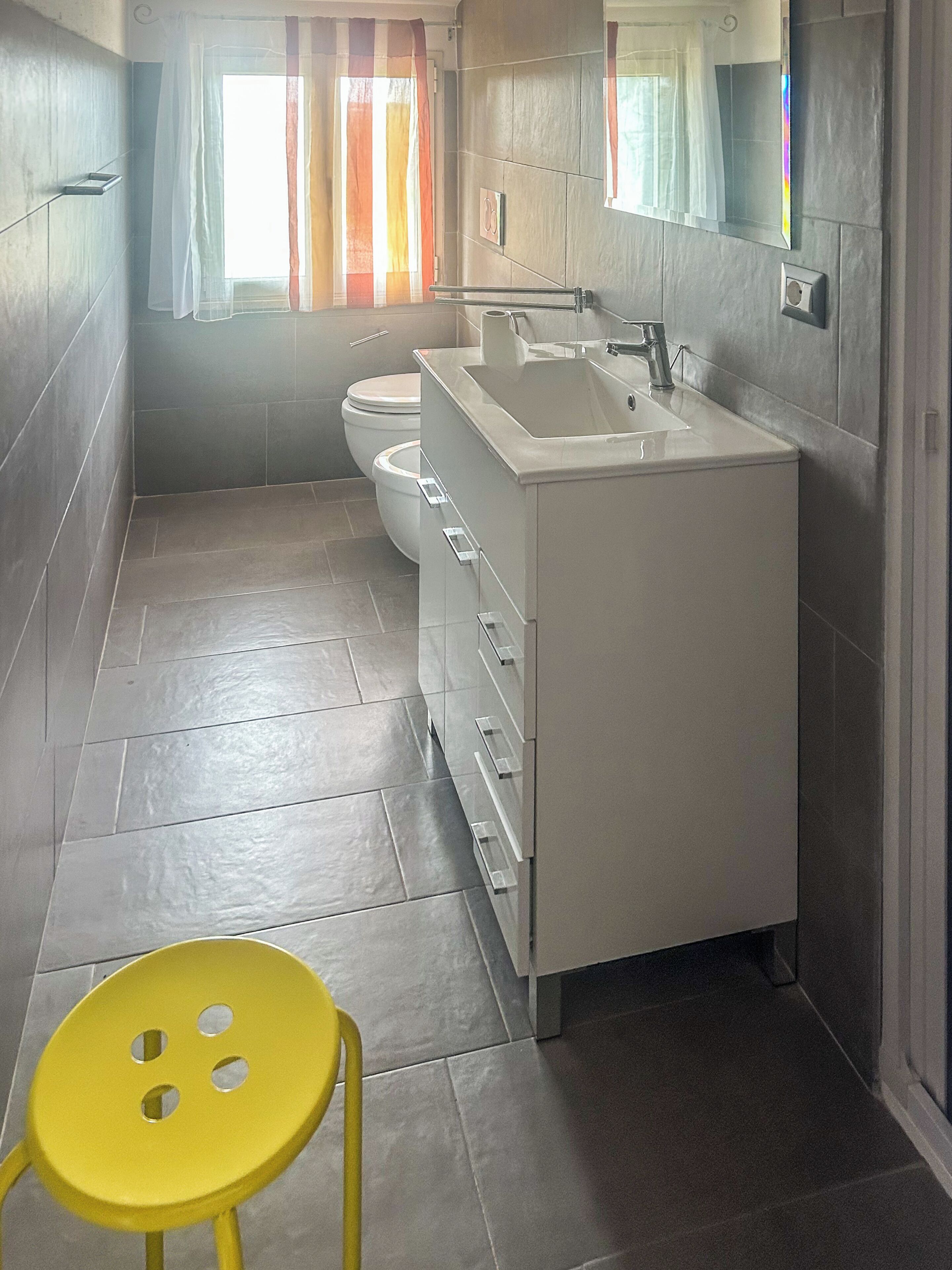 Un bagno con lavandino, specchio e water bianchi.