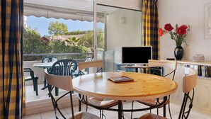 A balcony with a table and chairs, a TV, and a vase with flowers. - Antibes Center Near the Sea: 2BR, Terrace, Parking, Wi-Fi (Antibes)