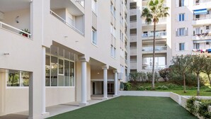 A modern building with multiple balconies, a courtyard with artificial grass, and a well-maintained garden area. - Antibes Center Near the Sea: 2BR, Terrace, Parking, Wi-Fi (Antibes)