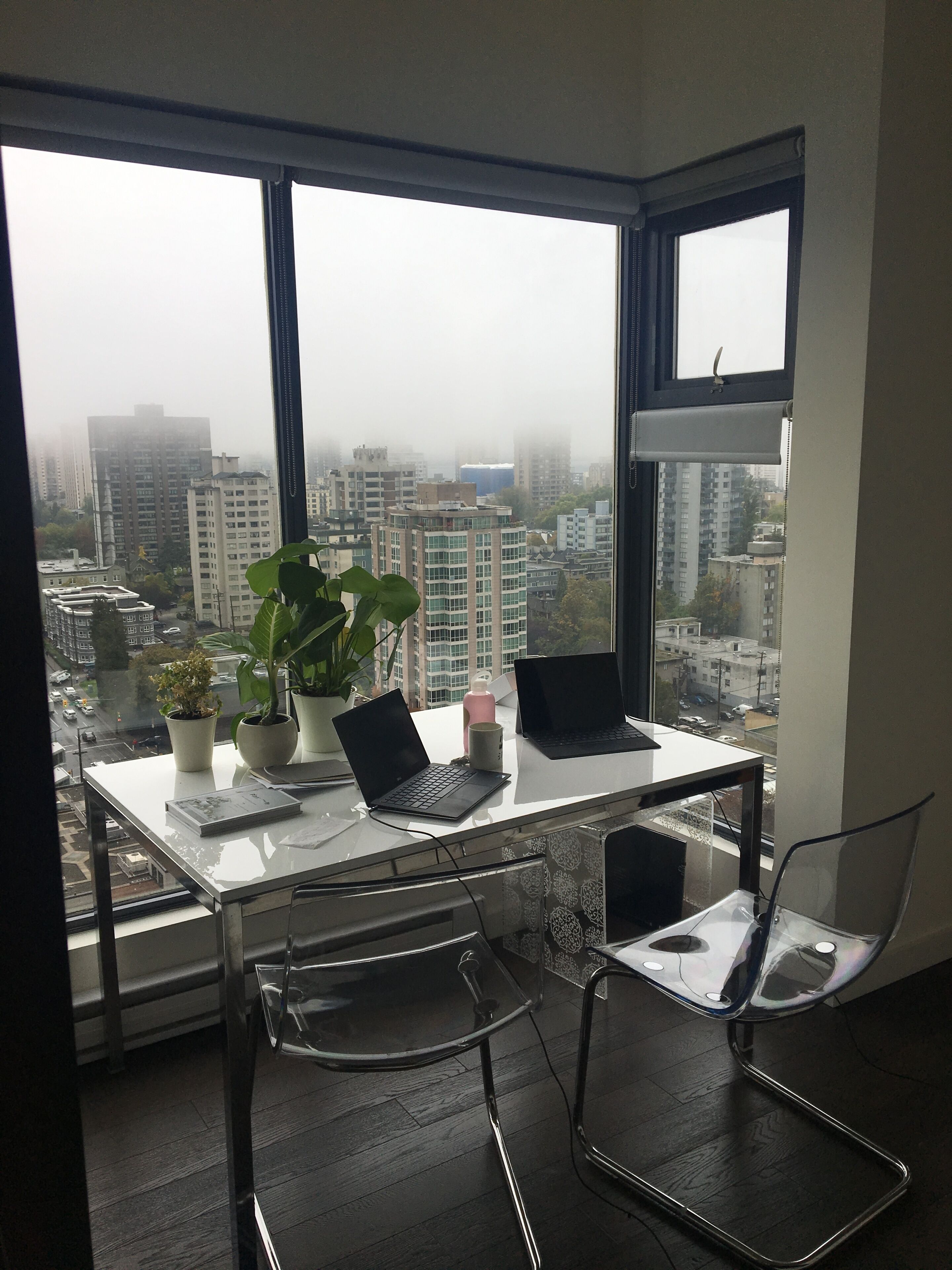 A modern office space with a desk, two laptops, a potted plant, and a chair.