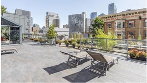Eine Dachterrasse mit Sitzgelegenheiten im Freien, Pflanzkübeln und Blick auf die Stadtlandschaft.