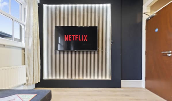 A room with a door featuring a vertical striped pattern, a black wall, and a wooden door on the right. - Elaine`s Central Stay (Nottingham)