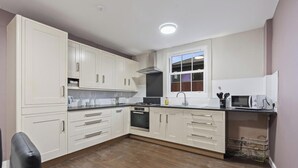 A kitchen with white cabinets, a stove, oven, and a window. - Elaine`s Central Stay (Nottingham)