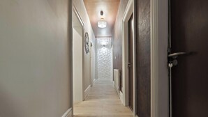 A hallway with a wooden floor, a radiator, and a door on the right. - Elaine`s Central Stay (Nottingham)