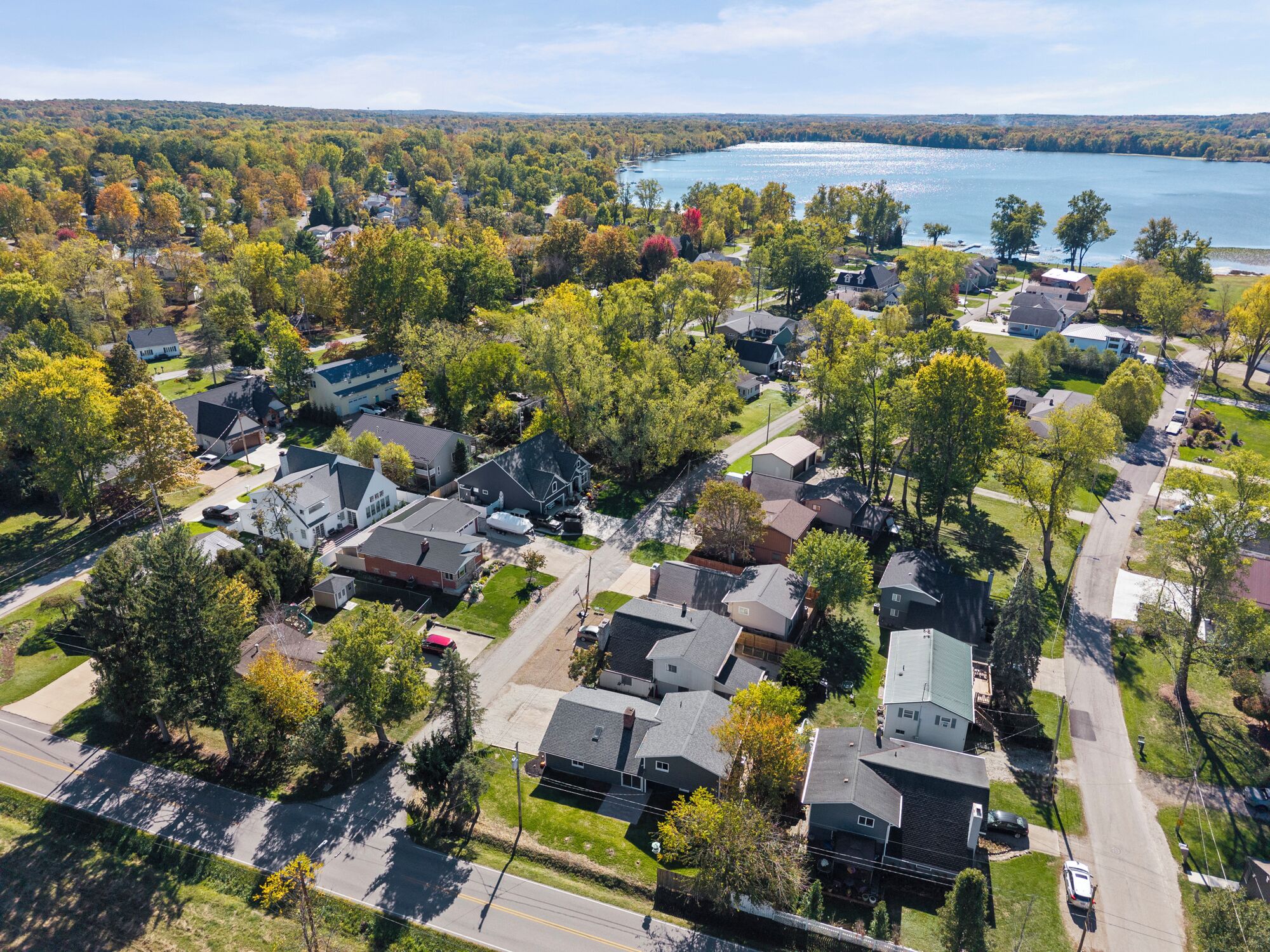 An aerial view of a residential area with houses, roads, and a lake.
