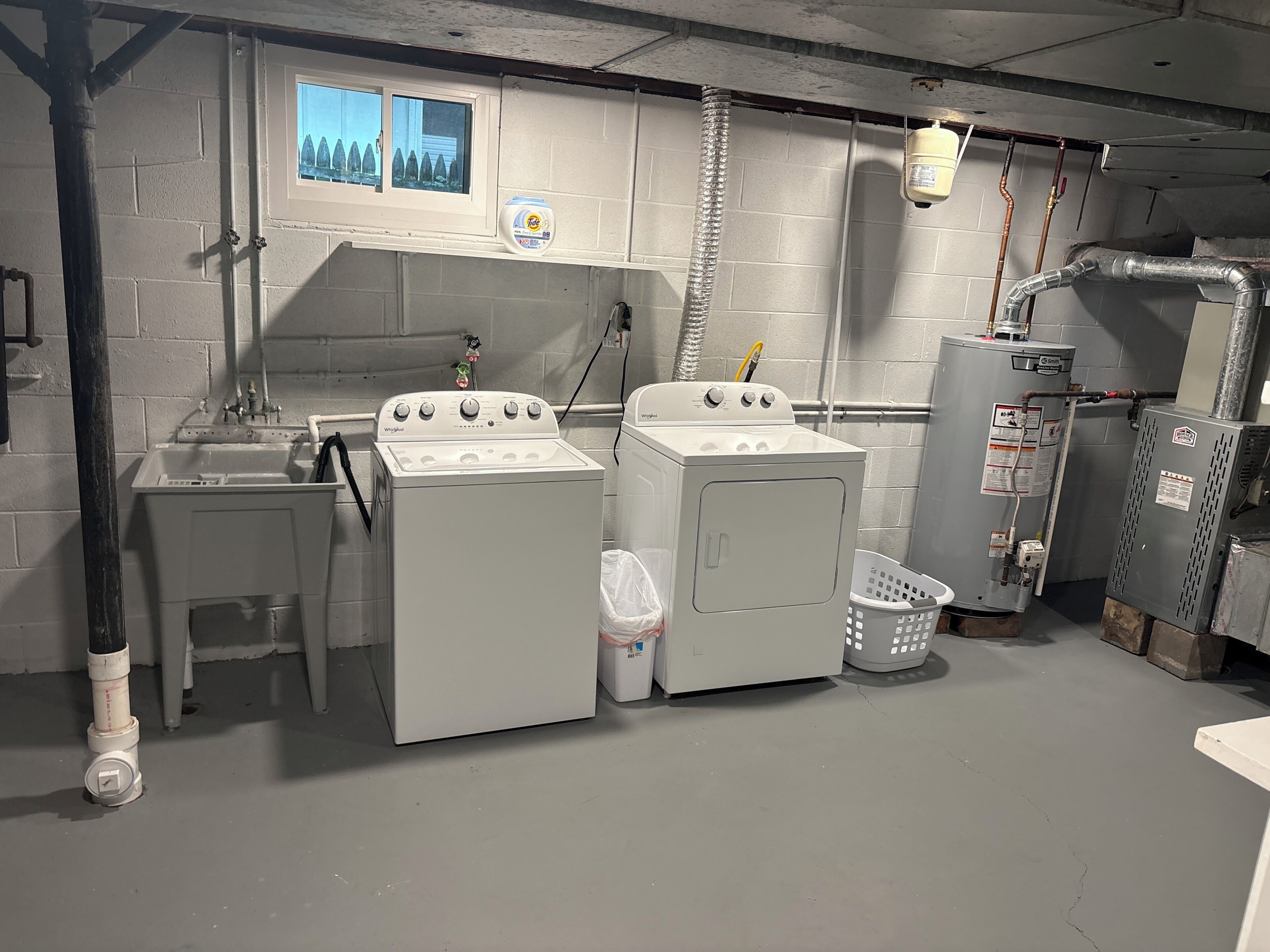 A laundry room with two washers and a dryer, a sink, and a window with a view.