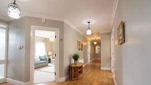 A hallway with wooden flooring, a potted plant, a wooden side table, and a framed picture on the wall. - An Grianán Getaway (Burt)