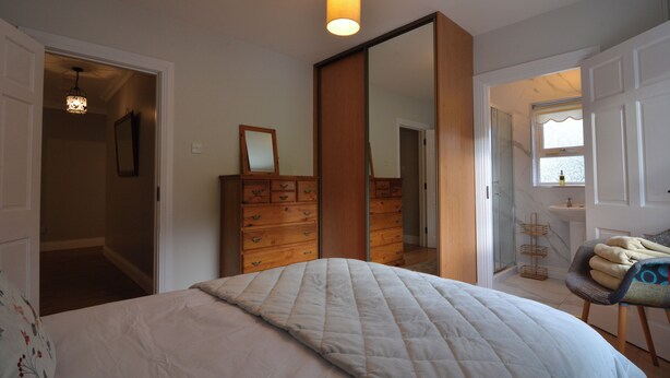 A bedroom with a bed, dresser, mirror, and a chair with towels. - An Grianán Getaway (Burt)
