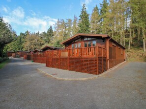 A row of wooden cabins with a fenced driveway, surrounded by trees. - No.14 Astbury Falls Luxury Retreat (Bridgnorth)
